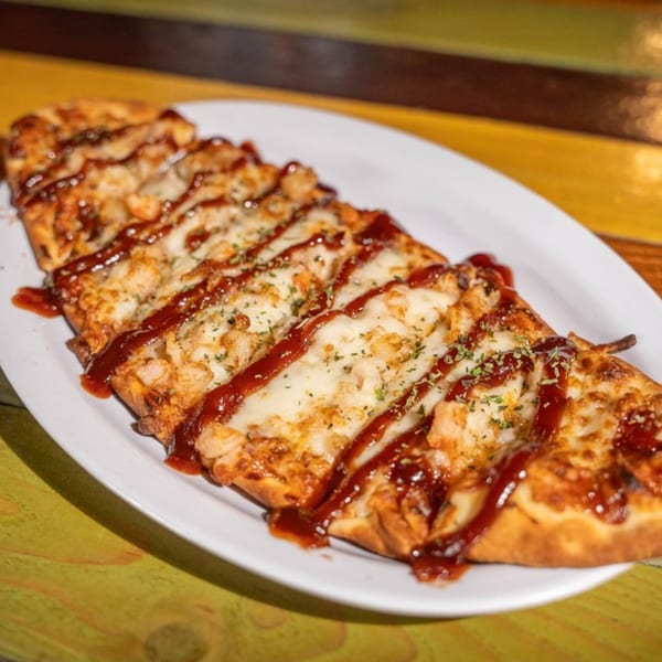 Nola Voodoo Tavern's Creole flatbread pizza, topped with melted cheese, chicken, and a drizzle of BBQ sauce.